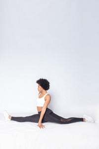 Shakolo crossover brain white and mid rise leggings in black side view model doing a split