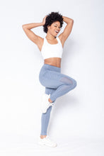 Load image into Gallery viewer, Shakolo crossover brain white and mid rise leggings in blue front view model one leg in the air and hands on head