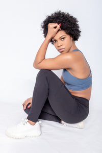 Shakolo high neckline bra in dark blue and high waist leggings side view with model sitting on the ground