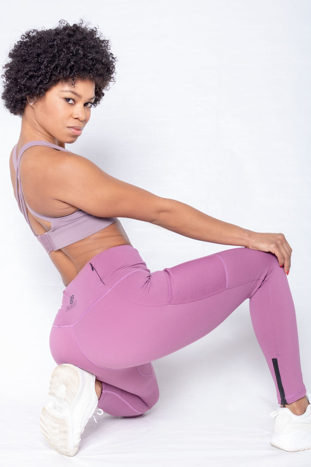 Shakolo adjustable strap bra in purple and high waist leggings in purple side view model with arm on bent leg