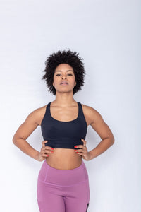 Shakolo crossover bra in black and high waist leggings in purple front view model with arms on waist