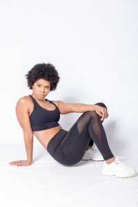Shakolo crossover bra in black and mid waist leggings in black side view model sitting on floor