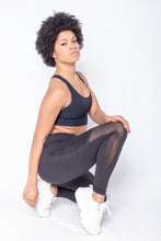 Load image into Gallery viewer, Shakolo crossover bra in black and mid waist leggings in black side view model squating with pointed toe