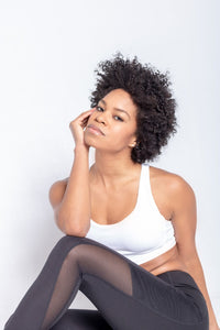 Shakolo crossover bra in white and high waist leggings in black front view model sitting on ground close up