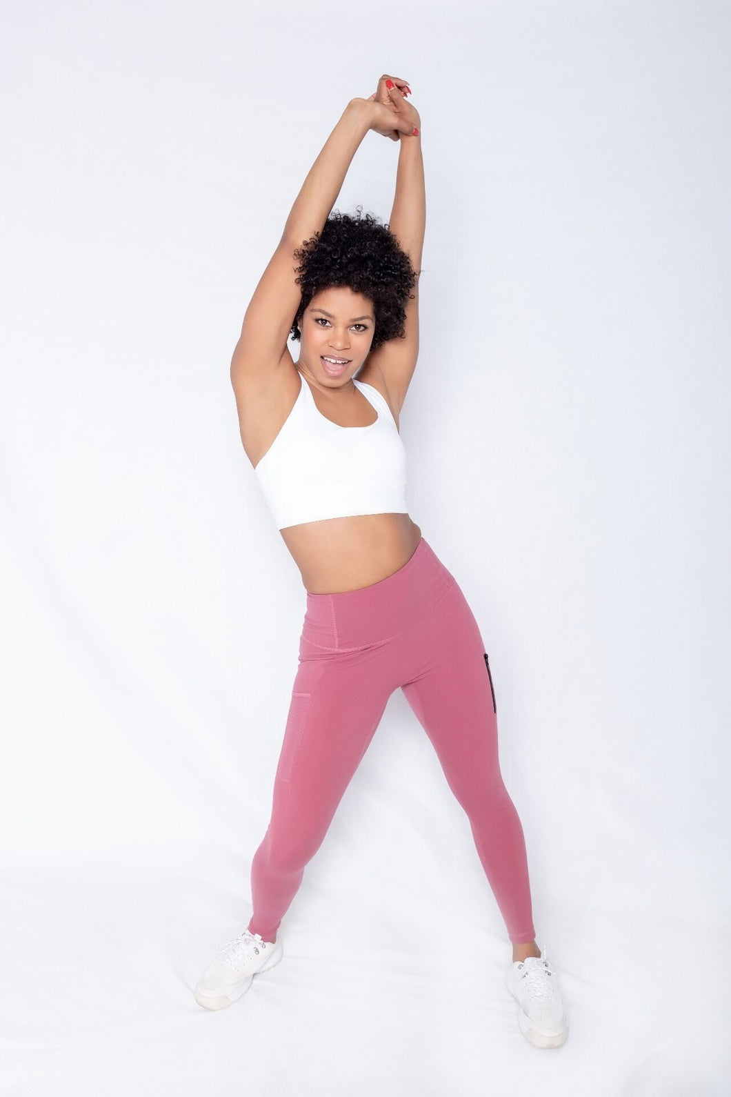 Shakolo crossover brain white and high waist leggings in pink front view model with two hands stretch over head
