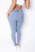 Load image into Gallery viewer, Shakolo mid rise leggings in blue back view with one hand in pocket