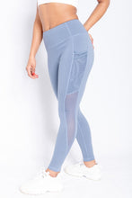 Load image into Gallery viewer, Shakolo mid rise leggings in blue side view with one leg forward and arm behind back